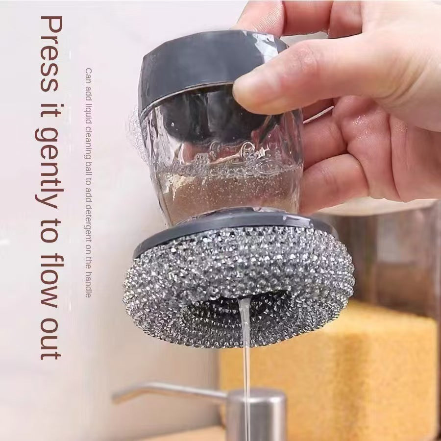 Hand holding a cleaning brush with liquid being dispensed from it, against a neutral background.